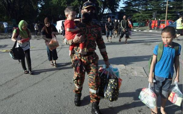 Anggota Jabatan Bomba dan Penyelamat Malaysia (JBPM) membantu membawa mangsa banjir untuk keluar dari kawasan banjir bagi menerima bantuan ketika tinjauan di Taman Sri Muda Seksyen 25 Shah Alam hari ini. - Foto Bernama