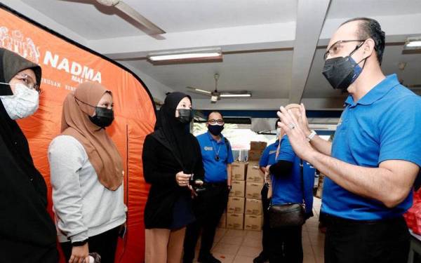 Ahmad Dasuki (kanan) meluangkan masa bersama mangsa-mangsa banjir di Pusat Pemindahan Sementara (PPS) di Jalan Klang Lama.