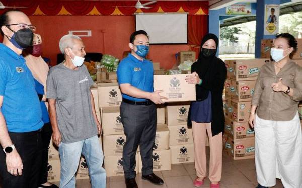 Wan Saiful menyerahkan kit bantuan banjir kepada salah seorang mangsa banjir di PPS di Jalan Klang Lama.