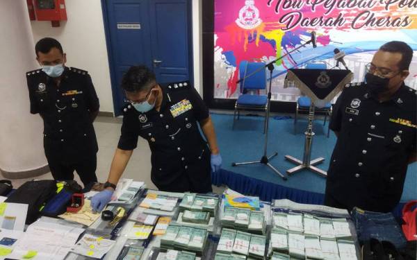 Muhammad Idzam (tengah) melihat barang yang dirampas pada sidang akhbar di IPD Cheras, Kuala Lumpur pada Rabu.