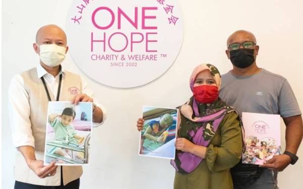 Sui Hou (kiri) dan ibu bapa Muhammad Aisy Aidan menunjukkan gambar anak mereka yang menghidap leukemia.