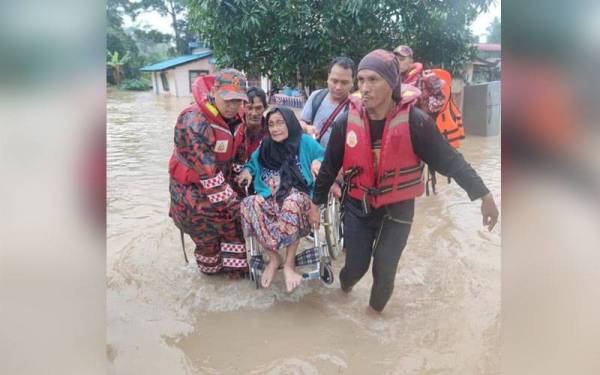 Anggota bomba menyelamatkan seorang warga emas yang terperangkap dalam banjir. Foto: FB JBPM