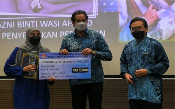 Khairy Jamaluddin (tengah) bersama Timbalan Ketua Pengarah Kesihatan (Penyelidikan dan Sokongan Teknikal) Datuk Dr Hishamshah Mohd Ibrahim (kanan) menyampaikan Anugerah Ungku Omar kepada Dr Nazni Wasi (kiri), pada Majlis Anugerah Penyelidikan Institut Kesihatan Negara (NIH) di Kompleks Institut Kesihatan Negara, pada Khamis. - Foto Bernama