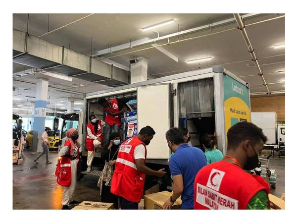 Sukarelawan Bulan Sabit Merah membantu memuatkan barangan keperluan ke dalam lori Lotus's.