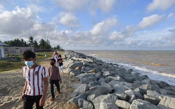 Sekumpulan kanak-kanak sedang berjalan melalui tepi benteng penahan ombak ketika cuaca cerah sewaktu tinjauan foto Bernama di Pantai Dasar hari ini.