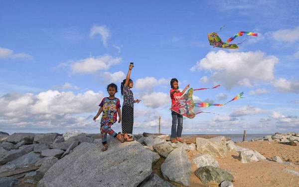 Sekumpulan kanak-kanak mengambil peluang ketika cuaca cerah bermain layang-layang di atas benteng penahan ombak sewaktu tinjauan foto Bernama di Pantai Dasar hari ini.