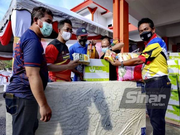 Mohd Salim (tengah) membantu membersihkan rumah mangsa banjir di Kampung Kuala Klawang.