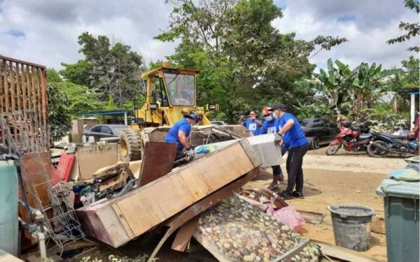 Mohd Shahar (kiri) turut membantu membersihkan kediaman penduduk di banjir di Perumahan Awam Kos Rendah Bukit Rangin di sini pada Sabtu.