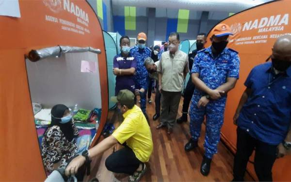 Dr Abd Latiff (duduk) bertanya sesuatu kepada salah seorang mangsa banjir ketika mengadakan lawatan di PPS Dewan Orang Ramai Paya Besar pada Jumaat.