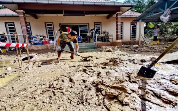 Muhammad Aiman membersihkan lumpur tebal di depan rumah keluarganya di Jelebu.