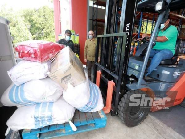 Dr Asmadi (kiri) bersama Zulkhairi (kanan) melihat barangan keperluan untuk mangsa banjir di depoh JKM di Kuantan pada Ahad.