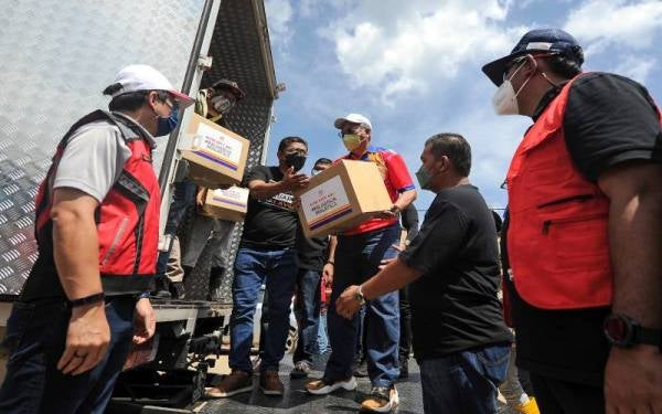 Annuar (tiga, kanan) bersama sukarelawan Komuniti Keluarga Malaysia KKMM dan Rumah Prihatin mengagihkan bantuan makanan dan keperluan harian kepada mangsa-mangsa banjir di Kampung Cennah. - Foto Bernama