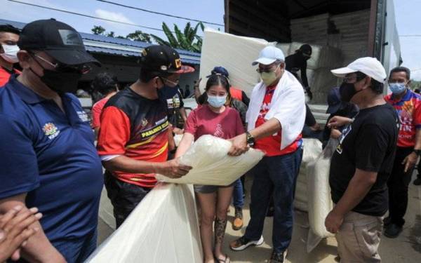 Annuar (tiga, kanan) bersama Jalaluddin (dua, kiri) mengagihkan tilam dan bantal kepada penduduk Kampung Cennah yang terjejas akibat banjir. - Foto Bernama
