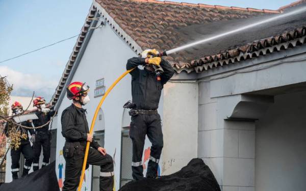 Anggota tentera dari unit kecemasan membantu membersihkan rumah penduduk yang diliputi debu gunung berapi Cumbre Vieja. - Foto AFP