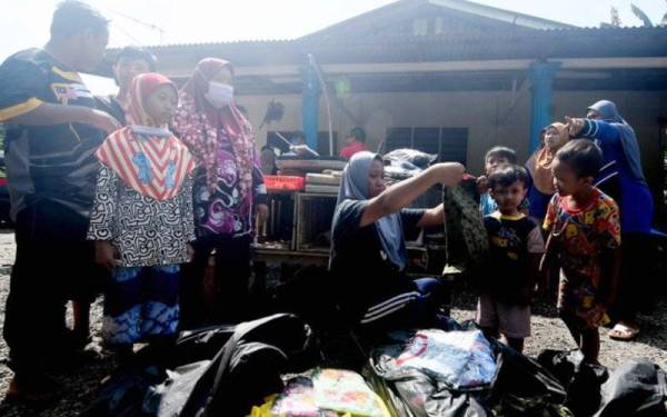 Penduduk kampung yang menjadi mangsa banjir memilih baju baharu yang disumbangkan oleh sukarelawan ketika tinjauan di Kampung Labohan Dagang Kuala Langat, Banting pada Ahad. - Foto Bernama