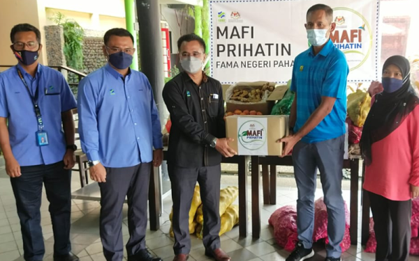 Rashid (tiga kiri) menyerahkan sumbangan pelbagai jenis sayuran kepada Mohd Norsham Nisam mewakili KYP Advanced Skills untuk dimasak dan diagihkan kepada mangsa banjir dan petugas barisan di daerah ini pada Isnin.