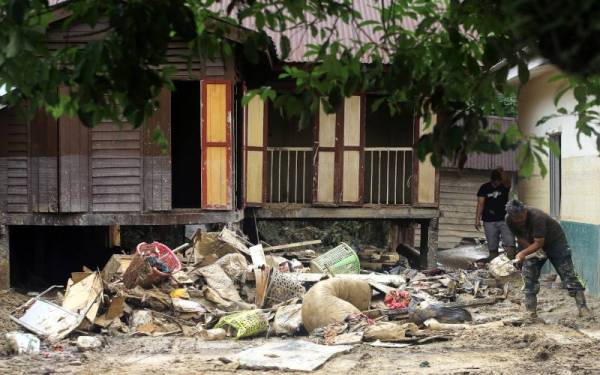 Dua penduduk di Kampung Batu Serambai membersihkan kediaman mereka selepas air surut dalam kejadian banjir beberapa hari lepas ketika tinjauan pasca bencana di sekitar Jelebu. - Foto Bernama