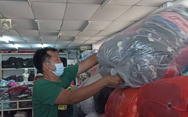 Pekerja premis pakaian milik Sofia Ab Hamid di bandar Kota Tinggi sedang sibuk meletakkan stok pakaian di tempat yang tinggi sebagai persiapan menghadapi kemungkinan banjir berlaku.