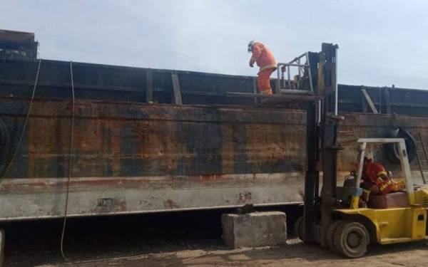 Anggota bomba sedang melakukan kerja-kerja memadamkan kebakaran dalam kejadian kapal tongkang meletup di Gat Leboh Macallum-Pengkalan Weld, Georgetown pada Selasa.