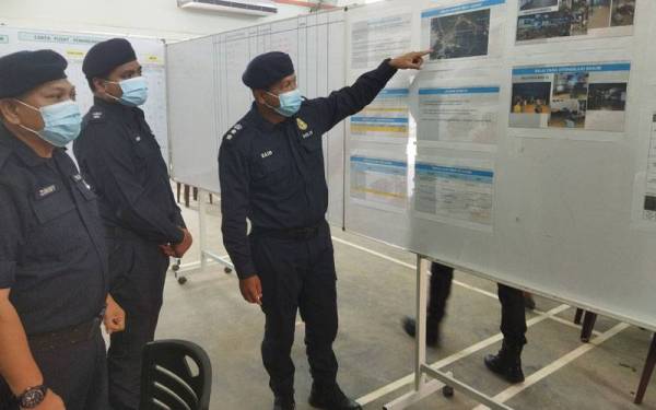 Mohd Zaid (kanan) melihat carta perkembangan terkini operasi pasca banjir di di Pusat Kawalan Operasi Banjir di sini pada Selasa.