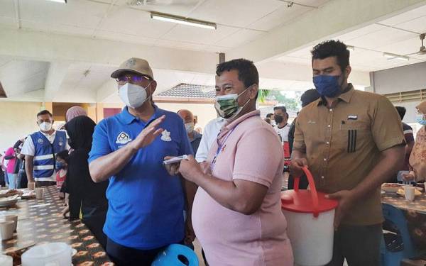 Wan Rosdy (kiri) menyampaikan sumbangan kepada mangsa banjir di pusat pemindahan sementara (PPS) Sekolah Menengah Kebangsaan Ubai, Pekan pada Selasa.