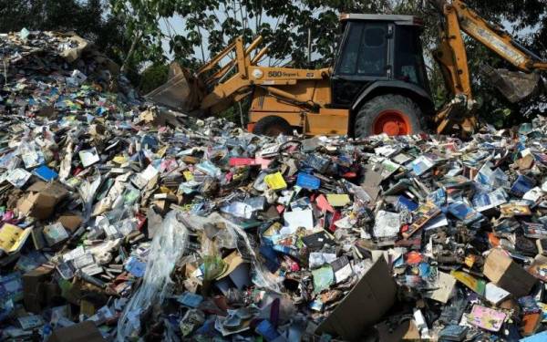 Pekerja gudang buku menggunakan backhoe untuk menolak kira-kira 2 juta buku yang rosak akibat banjir minggu lalu ketika tinjauan di gudang buku The Big Wolf Seksyen 33 Shah Alam. - Foto Bernama