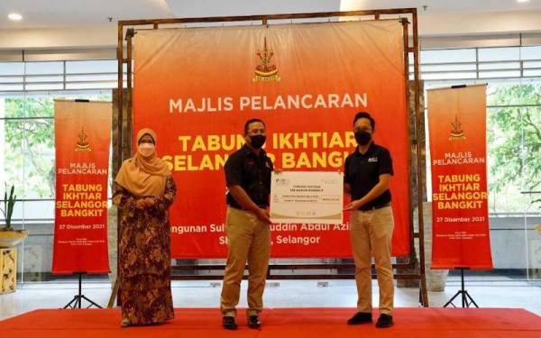 Amal menyerahkan replika cek sumbangan RM20,000 kepada Amirudin (tengah).