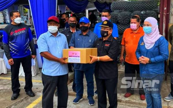 Ahmad Hamzah (dua,kanan) bersama Azulita (kanan) ketika penyerahan bantuan kepada ahli terjejas di PPK Temerloh pada Khamis.