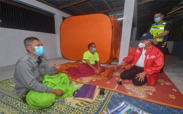 Mustapa (dua, kanan) menyantuni mangsa banjir yang terdiri daripada golongan warga emas di PPS Dewan Kesedar Sungai Satan malam tadi. - Foto Bernama