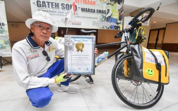 Wan Hashim menunjukkan sijil MBOR selepas menamatkan kayuhan solo jelajah mengelilingi Semenanjung Malaysia buat kali ketujuh di pekarangan Bangunan Mabna-MBI Kompleks Kota Darulnaim, pada Jumaat. - Foto Bernama 