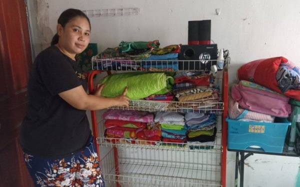 Noraini mengemas pakaian sebagai persediaan menghadapi bencana banjir di Kampung Pasir Johor Bahru.