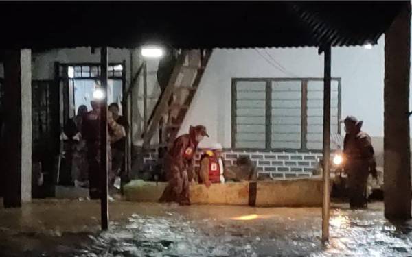 Anggota bomba membantu memindahkan mangsa banjir yang terkandas di Kampung Tengah, Segamat ke PPS berdekatan.