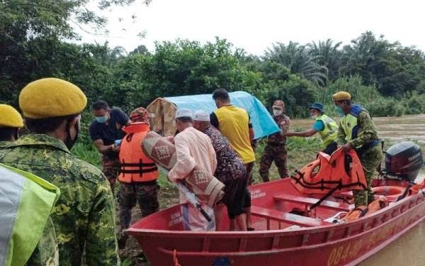 Anggota keselamatan membantu membawa jenazah seorang wanita warga emas ke Tanah Perkuburan Islam Kampung Padang, Setiu pada Sabtu selepas laluan di kawasan berkenaan dinaiki air. - Foto ihsan Bomba