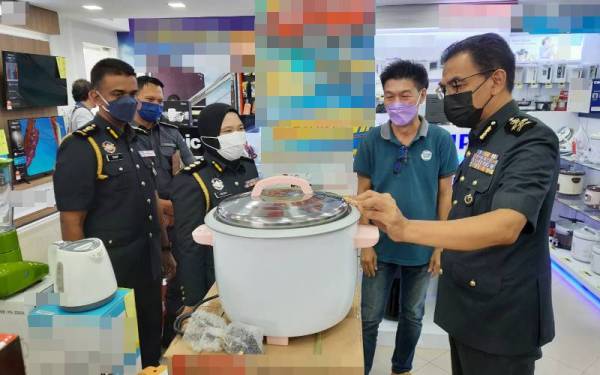 Azman (kiri) memeriksa harga perkakas elektrik dalam Ops Cakna di bawah AKHAP 2011 di sebuah kedai perabot dan barangan elektrik di Kuantan pada Sabtu.