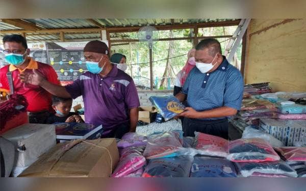 Mohd Nizar (kanan) melihat barangan yang berjaya dikumpul di Pusat Pengumpulan Sumbangan untuk Mangsa Banjir di de'Arena @Pasir Gajah di Parit.