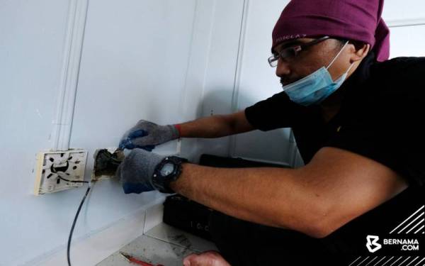 Seorang daripada sukarelawan yang melakukan pemeriksaan suis serta soket dirumah mangsa banjir secara percuma. - Foto Bernama