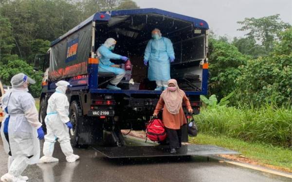 Anggota APM membantu memindahkan seorang mangsa banjir yang positif Covid-19 dari Felda Palong Timur, Batu Anam, Segamat ke HDS pada Ahad.