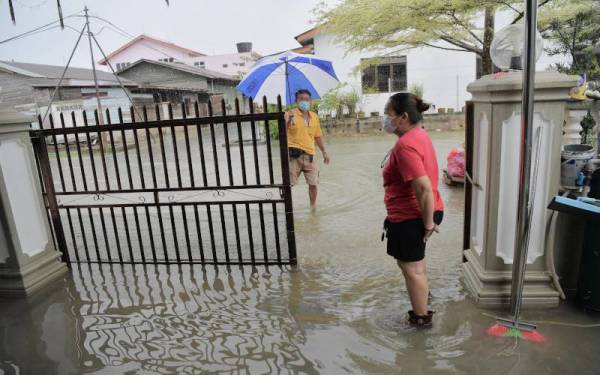Beberapa penduduk Taman Gembira, Segamat resah dan sentiasa memantau paras air yang mula membanjiri kawasan perumahan mereka kira-kira ke paras betis. - Foto Bernama