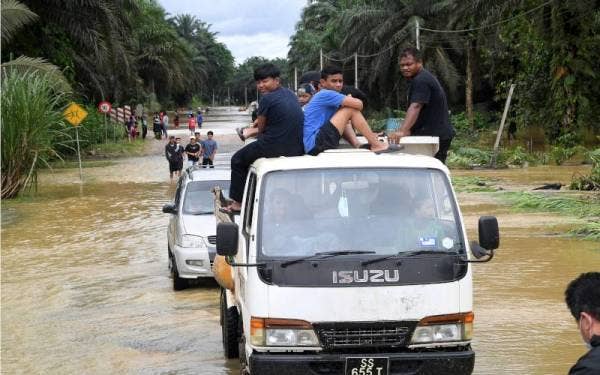 Orang ramai menaiki lori untuk keluar selepas banjir melanda Kampung Sungai Manjang sejak semalam ketika tinjauan pada Ahad. - Foto Bernama 