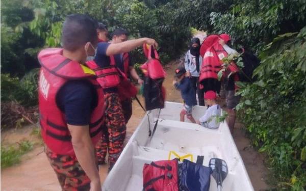 Anggota bomba membantu memindahkan enam mangsa banjir di Kampung Tanah Banjir Tebing Tinggi, Segamat, pada Ahad.