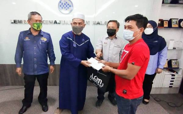 Syed Abu Hussin menyampaikan bantuan kepada salah seorang nelayan di daerah Kuantan yang terjejas banjir pada majlis penyerahan bantuan itu di Wisma LKIM di sini pada Isnin.