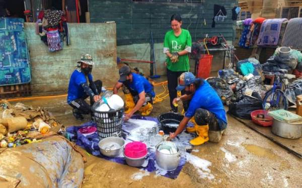 Sukarelawan Wasco Coatings Kuantan membersihkan peralatan milik mangsa banjir dalam misi bantuan syarikat itu di Mentakab