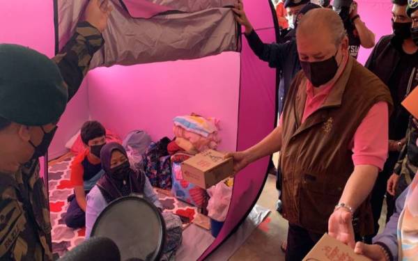 Sultan Ibrahim menyampaikan makanan tengah hari kepada salah seorang mangsa terjejas di PPS SK Mawai di sini pada Isnin