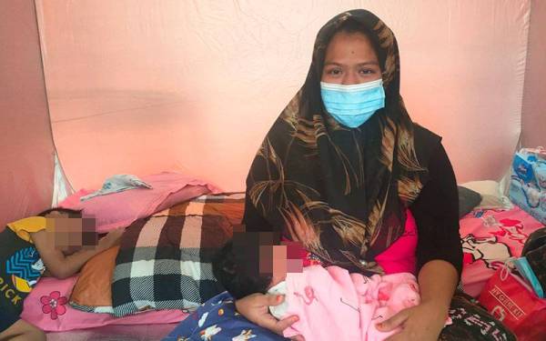 Awadah Fatin meriba bayi perempuannya berusia 14 hari di PPS SK Krubong, di sini, pada Isnin.