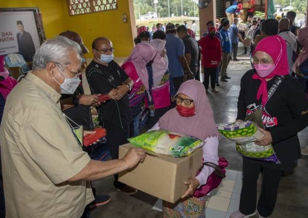 Annuar (kiri) mengagihkan bantuan makanan keperluan harian dan bantuan kewangan kepada mangsa banjir di Sekolah Kebangsaan (SK) Kuala Balah hari ini. -Foto Bernama