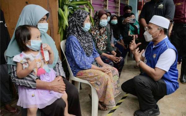 Menteri di Jabatan Perdana Menteri (Hal Ehwal Agama), Senator Idris Ahmad beramah mesra dengan adik-beradik mangsa banjir (dari kiri) Zaharah, Zainab dan Zanariah di PPS Sekolah Agama Kuala Paya Segamat. - Foto Bernama