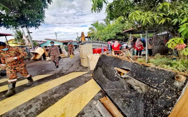 Anggota bomba turun padang membantu operasi pembersihan rumah penduduk.
