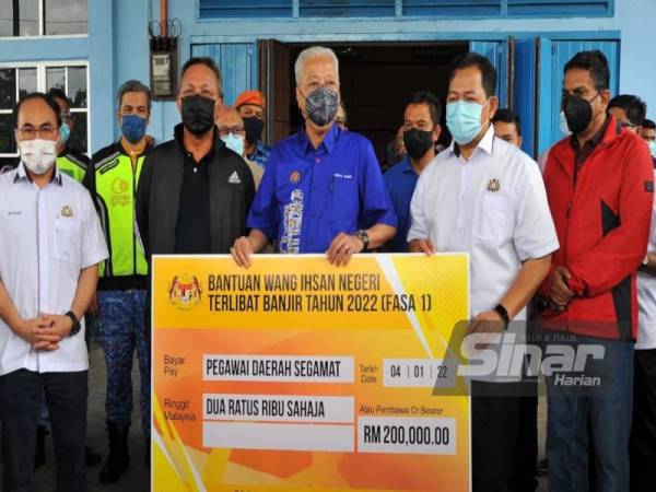 Ismail Sabri (tengah) menyampaikan wang ihsan kepada mangsa banjir yang ditempatkan di PPS Balai Raya Kampung Tandong, Segamat pada Selasa.