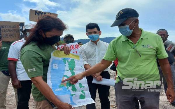 Meor Razak (kanan) menunjukkan lot kawasan perlombongan pasir yang berlaku di kawasan KSAS tahap satu yang juga habitat penyu bertelur di Pantai Pasir Panjang, Segari pada Selasa.