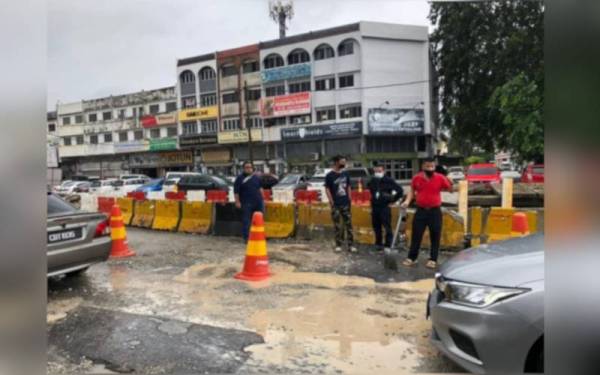 Chon Siang (kanan) mengambil keputusan menampal jalan berlubang di Jalan Beserah selepas mendapati tiada tindakan diambil pihak berkaitan.